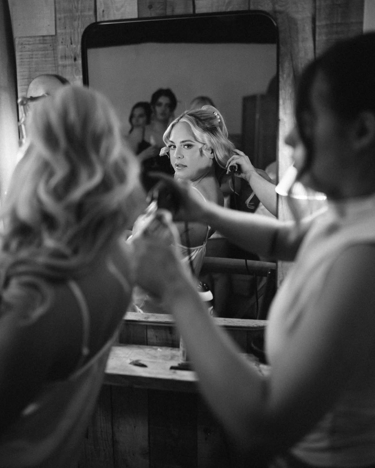 Bride watching in the mirror as her hair is styled on the wedding morning